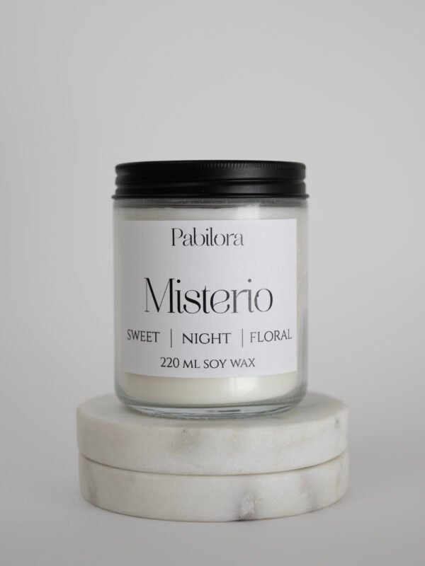 Pabilora Misterio scented candle: a sweet nocturnal blend of citrus and pear with a delicate floral heart of iris, jasmine, orange blossom, and violet, finished with a warm base of musk, amber, patchouli, vetiver, and vanilla.