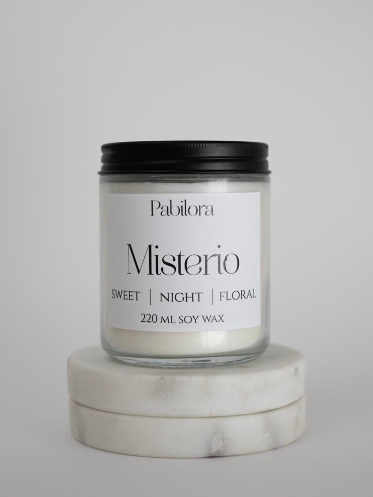 Pabilora Misterio scented candle: a sweet nocturnal blend of citrus and pear with a delicate floral heart of iris, jasmine, orange blossom, and violet, finished with a warm base of musk, amber, patchouli, vetiver, and vanilla.
